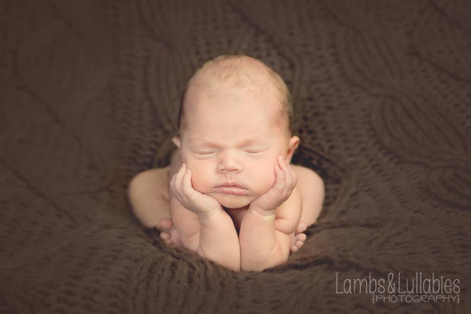 newborn baby boy with head in hands