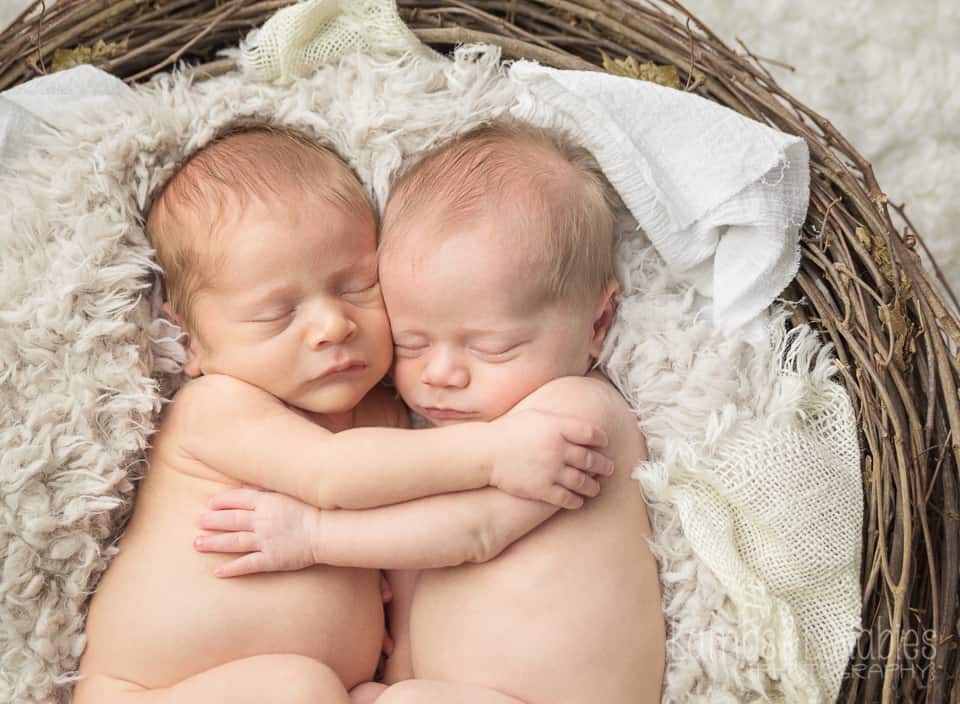 twin newborn babies hugging