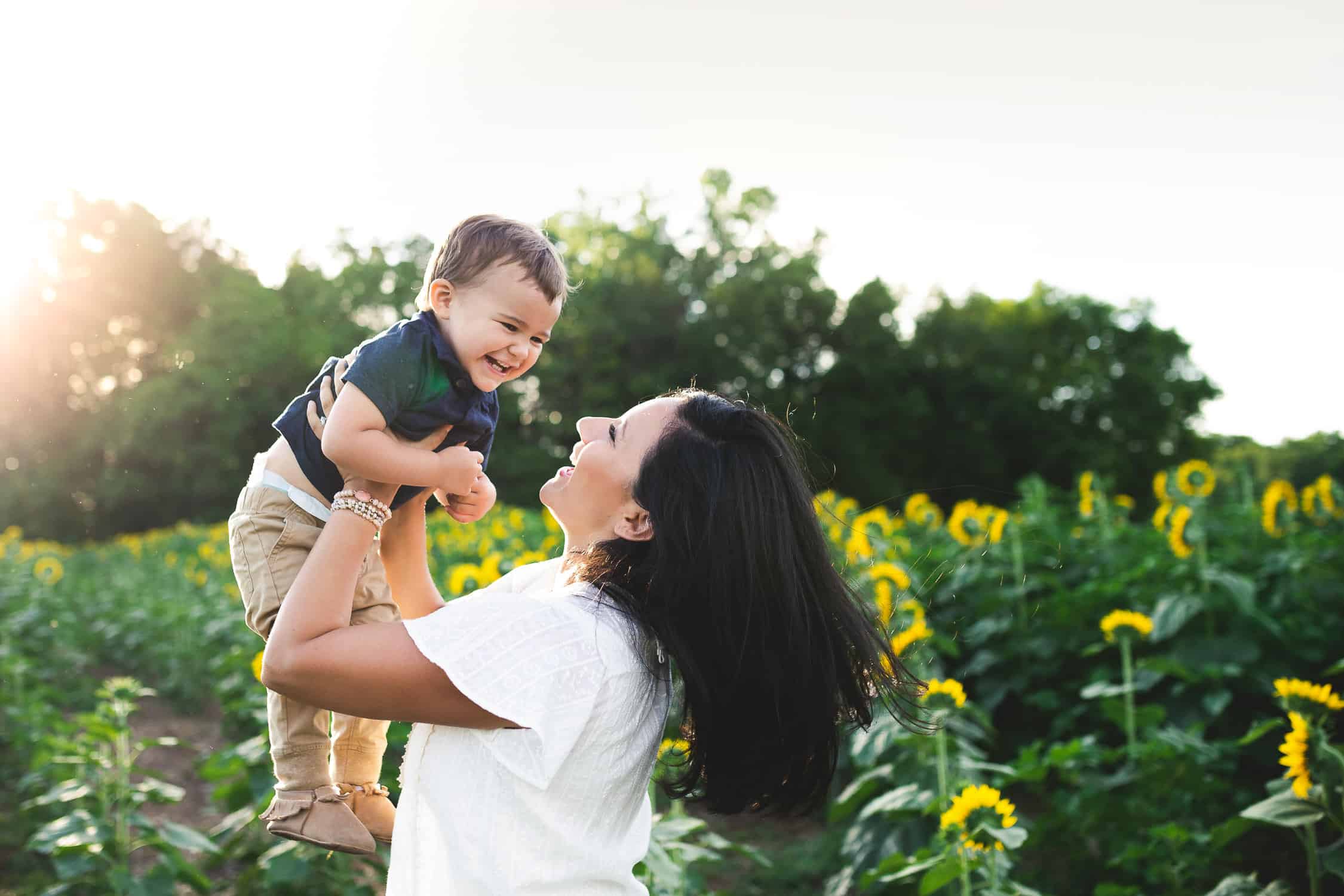 Baby boy thrown in the air by mom in a sunflower field in Kansas City