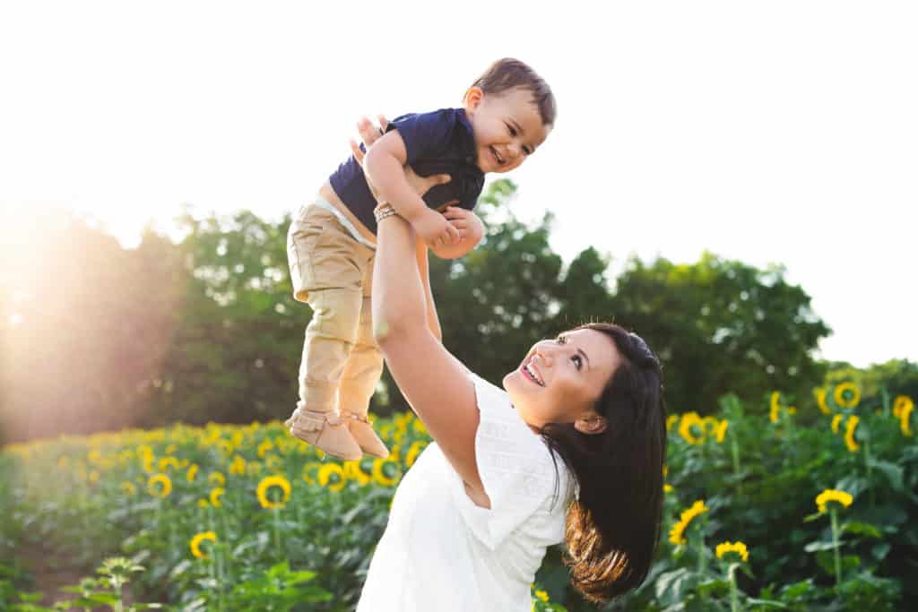 mom and toddler playing in a sunflower field