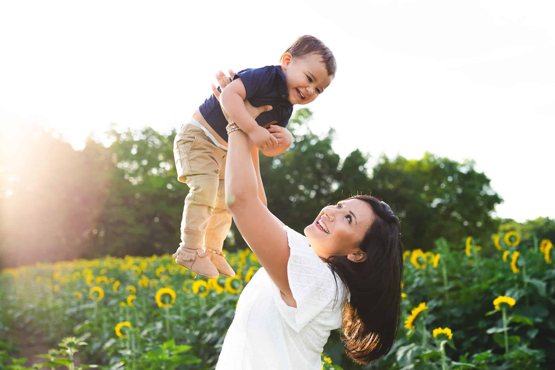 mom and toddler playing in a sunflower field