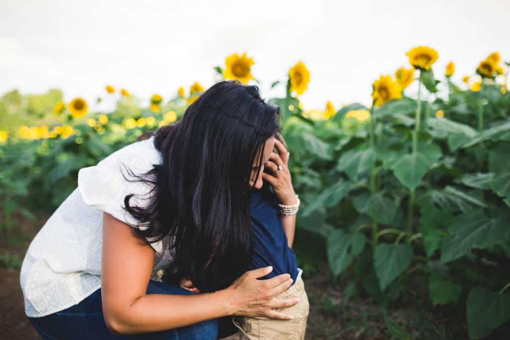 Mom hugging child in sunflower field in Kansas City