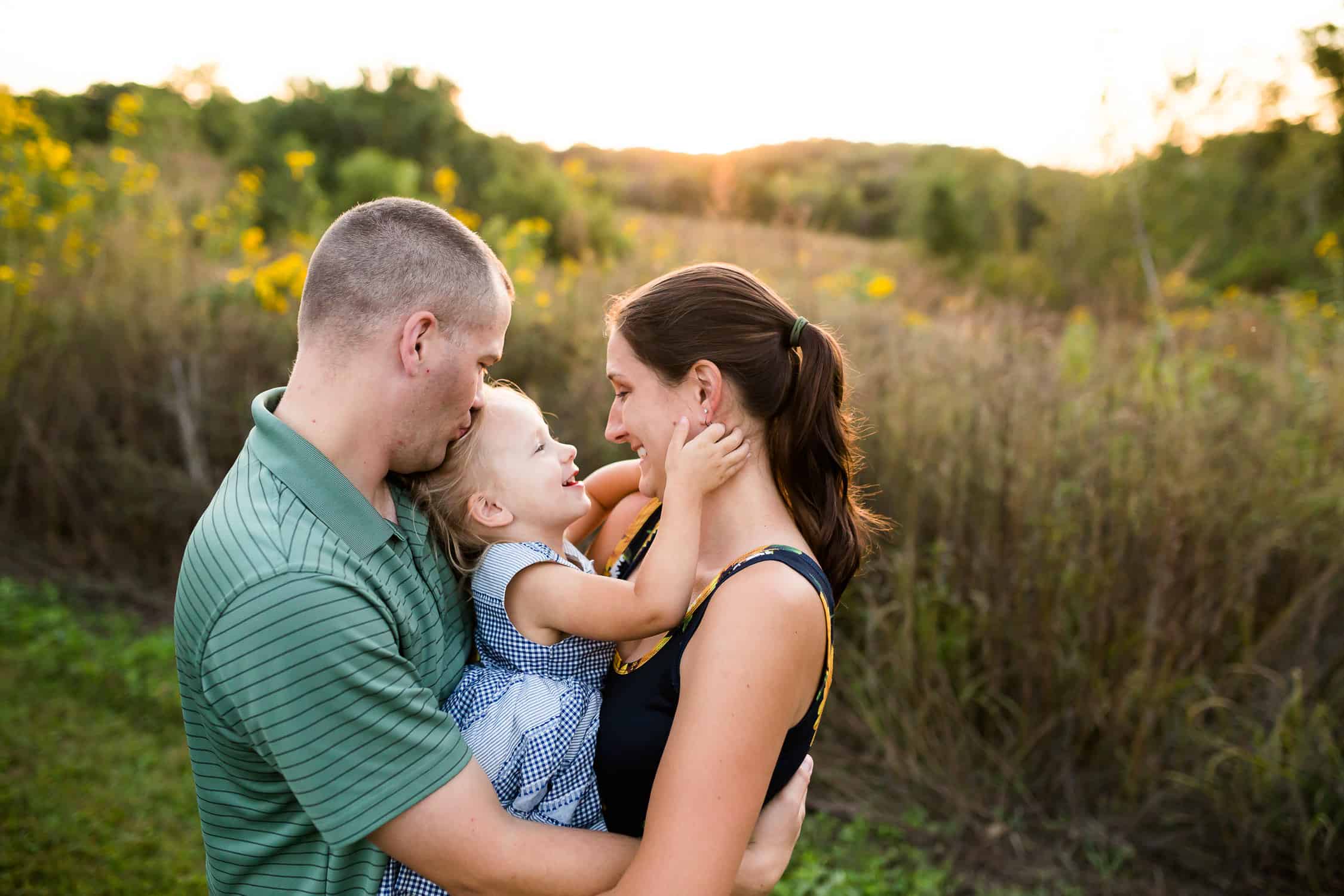 Mom and dad snuggle daughter for family photos