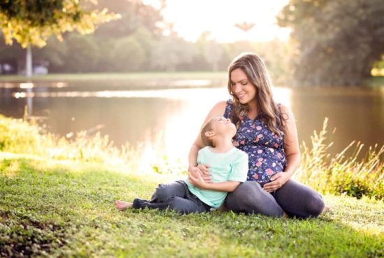 Pregnant mother and son sitting in the grass for her maternity photography session