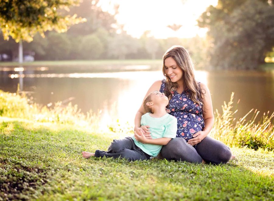 Pregnant mother and son sitting in the grass for her maternity photography session