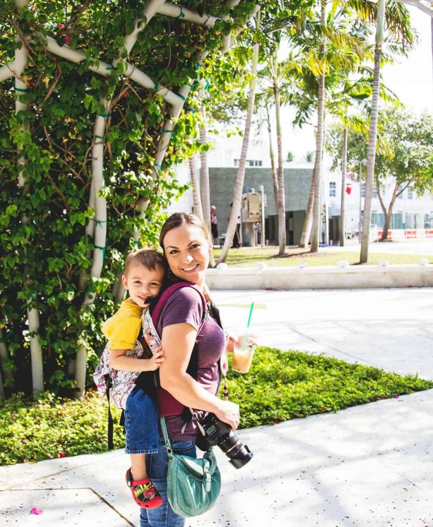 Renee Barber of Lambs and Lullabies Photography holding her son on her back