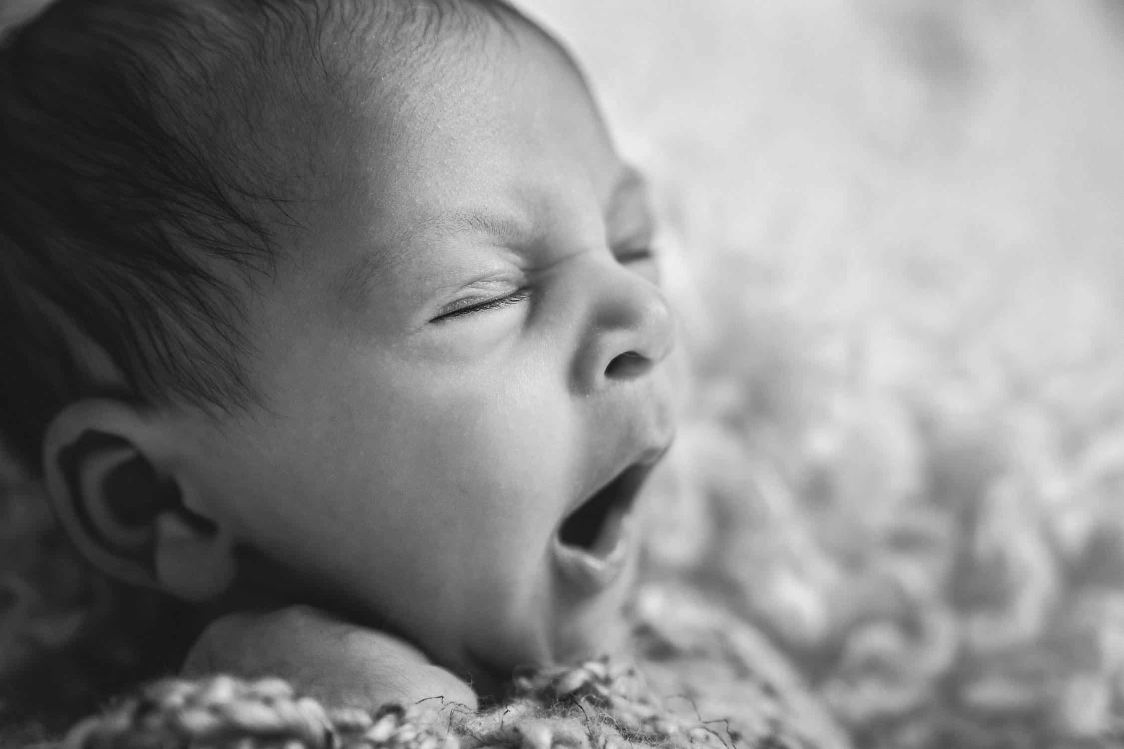 3 week old newborn yawning in closeup black and white image