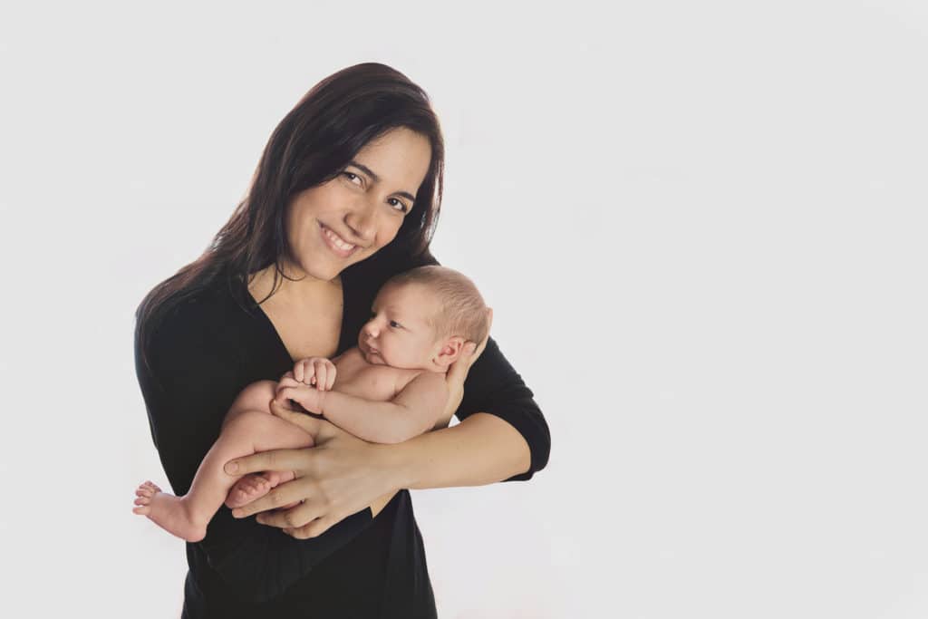 newborn photos kansas city mom holding baby boy and smiling