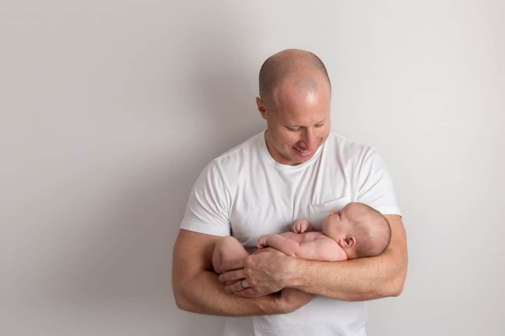 kansas city newborn photography dad holding baby girl and smiling